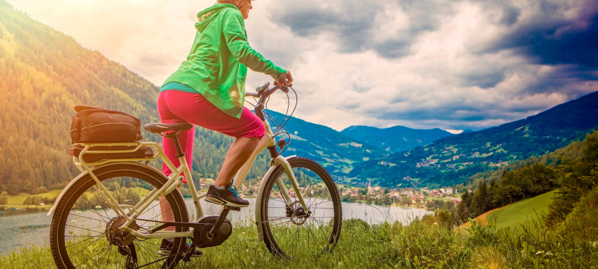 sportive woman with e-bike above a lake